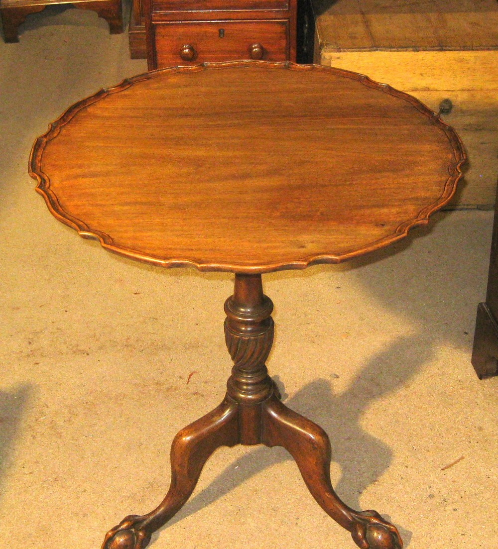 A Victorian mahogany tilt-top table with a piecrust scalloped border, turned pedestal, and tripod legs ending in claw and ball feet.