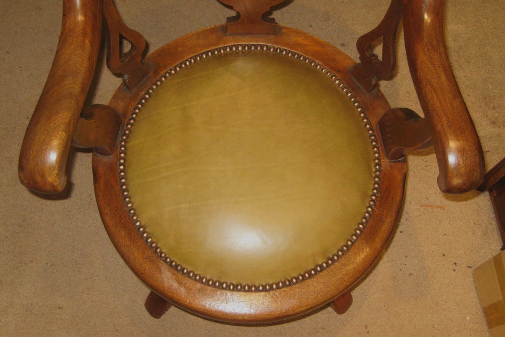 A Victorian golden mahogany revolving desk chair featuring a curved horseshoe backrest, pierced vasiform splat, leather seat with brass studs, and four splayed cabriole legs. View II
