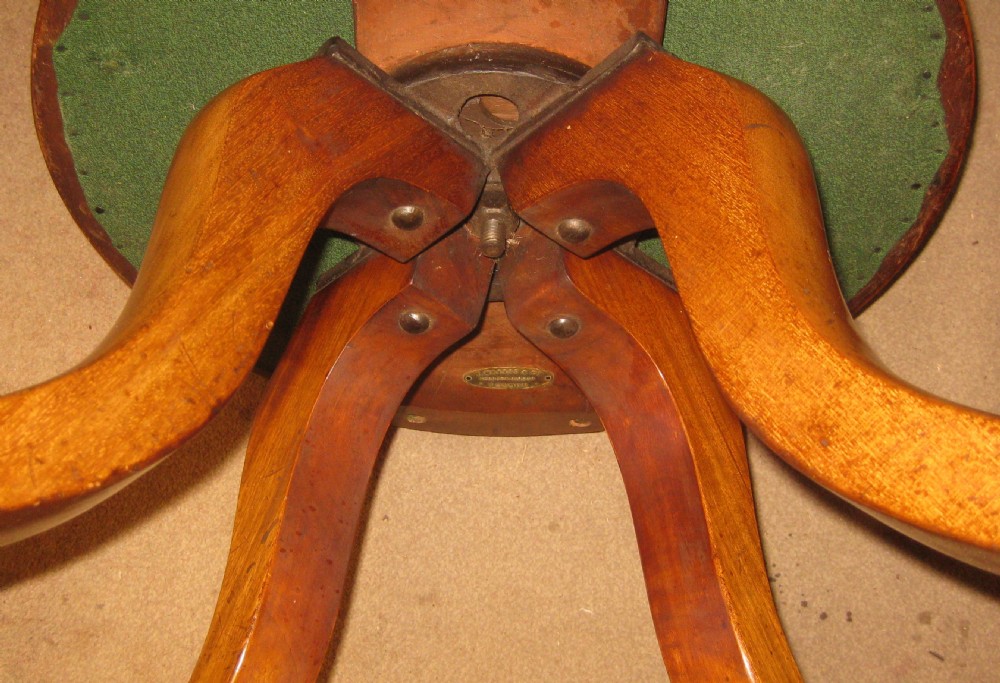 A Victorian golden mahogany revolving desk chair featuring a lyre-shaped back splat, curved horseshoe arms, and a circular padded leather seat trimmed with brass studs. View VIII