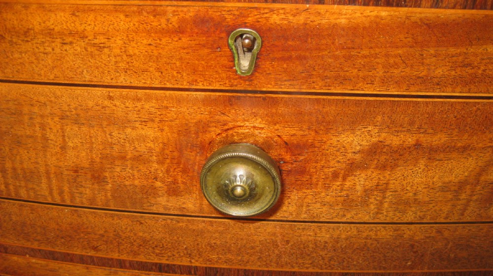 An early Georgian golden mahogany bow-fronted chest of drawers featuring two short drawers over two long drawers with brass knobs and inlaid crossbanding. View III