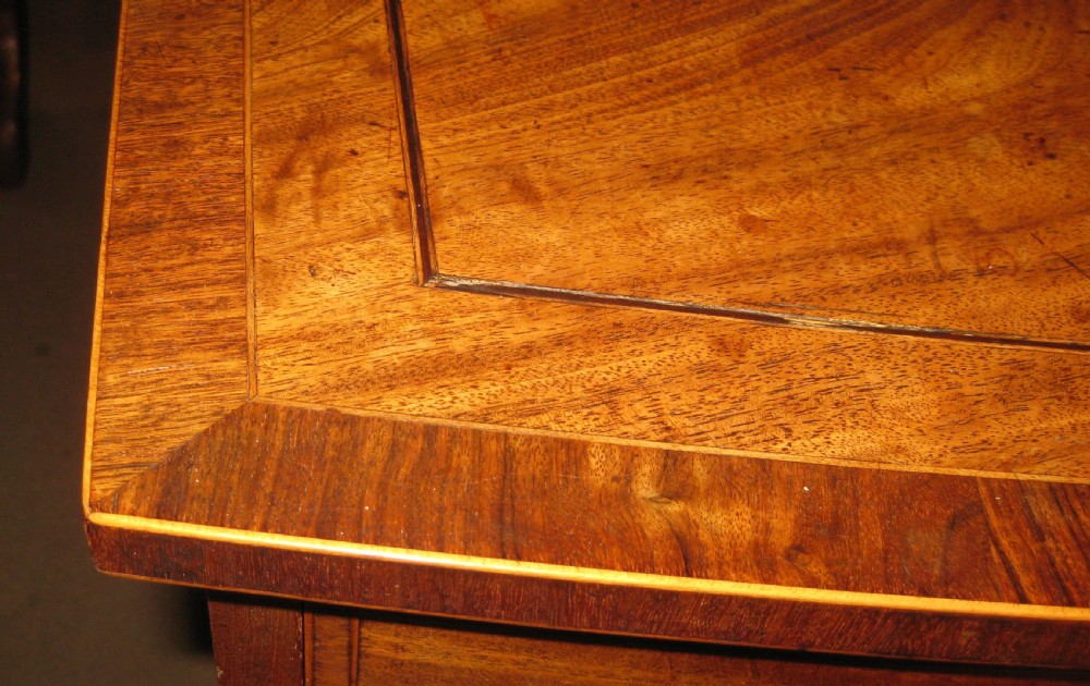 An early Georgian golden mahogany bow-fronted chest of drawers featuring two short drawers over two long drawers with brass knobs and inlaid crossbanding. View V