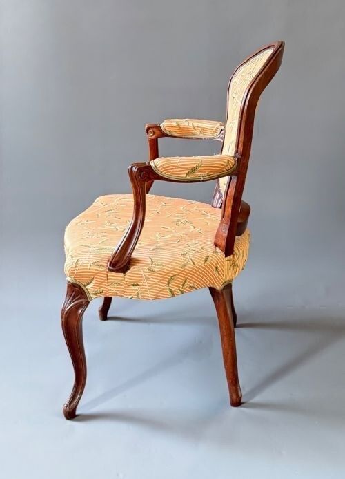fig 1. A mid-18th century French Hepplewhite armchair featuring a carved timber frame, cabriole front legs, and peach striped silk upholstery with leaf patterns.