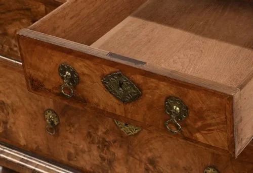 fig 1. An antique William and Mary walnut secretaire chest featuring figured walnut veneers, a fall-front upper section, multiple drawers, and turned bun feet.