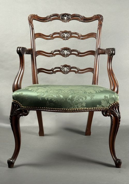 An 18th-century George III mahogany armchair featuring pierced ladder-back rails, curved armrests, cabriole front legs, and a green damask upholstered seat.