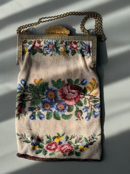 fig 1. A collection of seven 1920s evening bags and purses featuring micro-beaded floral designs, glass beadwork, and silver metal mesh with ornate clasps.