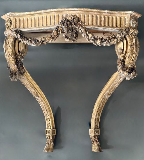 A 19th-century French carved giltwood console table base featuring a fluted apron decorated with floral festoons and supported by curved cabriole legs.