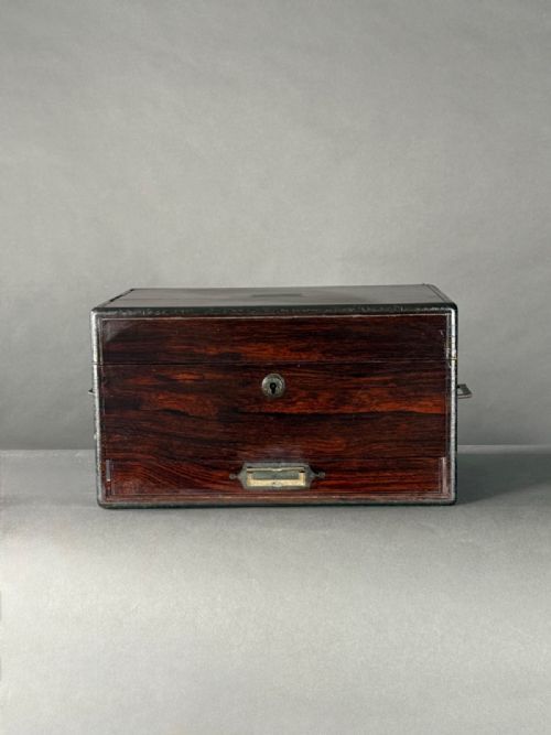 fig 1. An open antique rosewood vanity box featuring a crimson velvet-lined lid, fitted glass jars, and an open lower drawer.