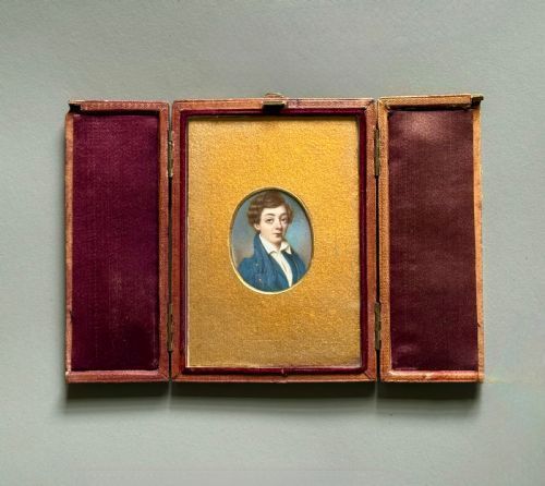 fig 3. An oval 19th-century portrait miniature depicting a young boy with brown hair wearing a blue jacket, set within a gilded frame.