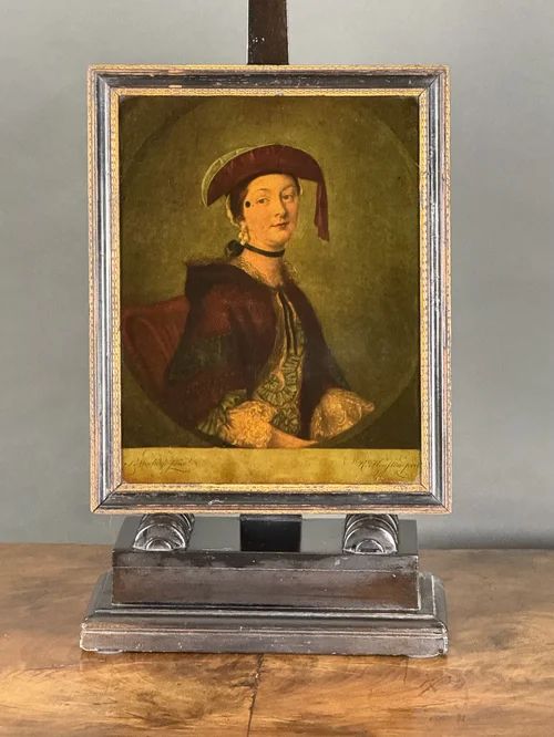 fig 1. An 18th-century reverse-painted glass mezzotint portrait depicting a woman in a velvet bonnet and cloak within an ebonised and gilt frame.