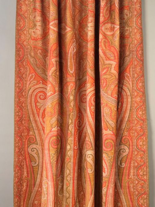 fig 3. A large Victorian woven wool shawl featuring dense teardrop Paisley patterns in shades of terracotta, ochre, and green with a fringed border.