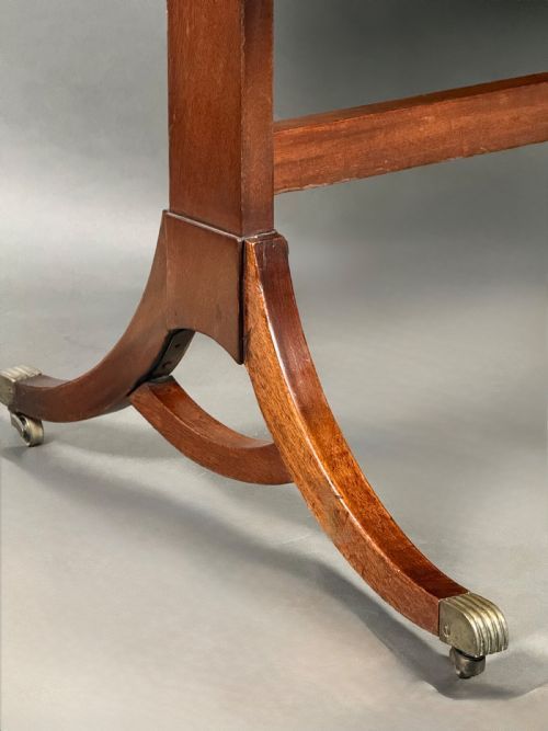 fig 1. A nineteenth-century flame mahogany sofa table featuring two drop leaves, twin pedestal legs with a low stretcher, and brass caps on castors.