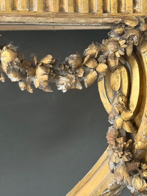 fig 1. A 19th-century French carved giltwood console table base featuring floral swags, a fluted frieze, and curved leg supports.