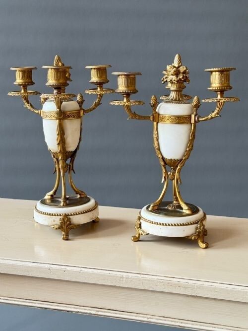 fig 1. A pair of French Neoclassical gilt bronze and white marble three-light urn-form candelabra featuring leaf-moulded branches and beaded circular bases.