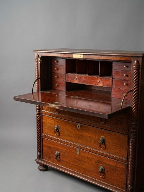 fig 2. A Regency mahogany secretaire bookcase featuring a glazed two-door cabinet, an open fall-front fitted writing drawer, and lower drawers flanked by rope-twist carved columns.