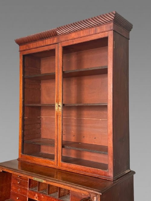fig 3. A Regency mahogany secretaire bookcase featuring a glazed two-door cabinet, an open fall-front fitted writing drawer, and lower drawers flanked by rope-twist carved columns.