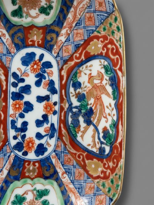 fig 1. An oblong 19th-century Japanese Imari porcelain dish with scalloped edges, decorated with hand-painted cobalt blue, orange, green, and gold floral and bird patterns.