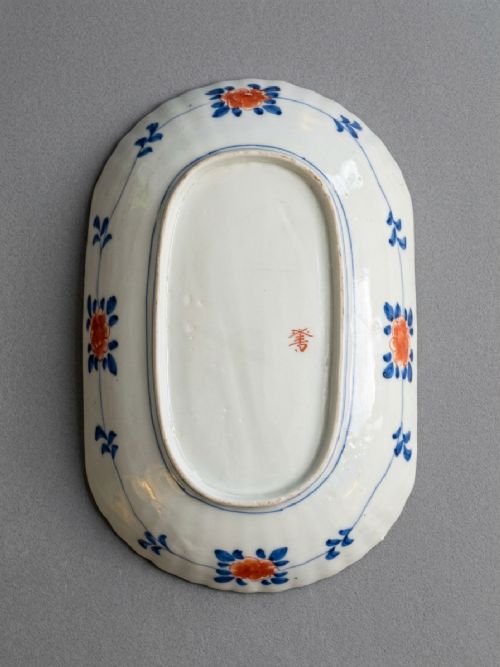 An oblong 19th-century Japanese Imari porcelain dish with scalloped edges, decorated with hand-painted cobalt blue, orange, green, and gold floral and bird patterns. View V