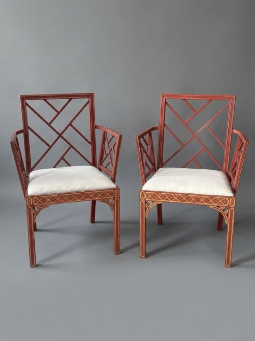 fig 1. A pair of red painted and gilded armchairs with geometric lattice backs and sides and light cream upholstered seats.