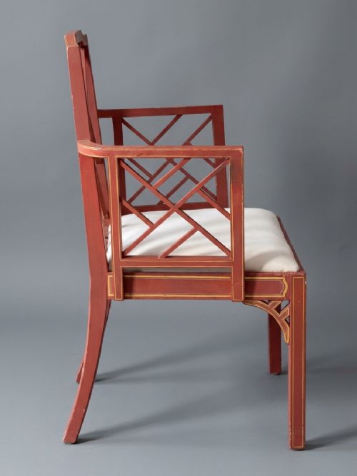 fig 2. A pair of red painted and gilded armchairs with geometric lattice backs and sides and light cream upholstered seats.