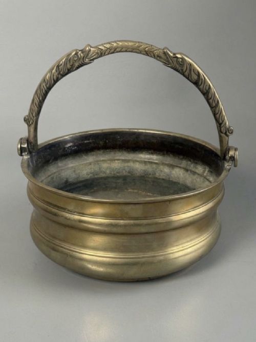 fig 1. An aged brass urn with caryatid supports and a top finial lid, displayed alongside a brass vessel featuring a raised dragon-form handle.