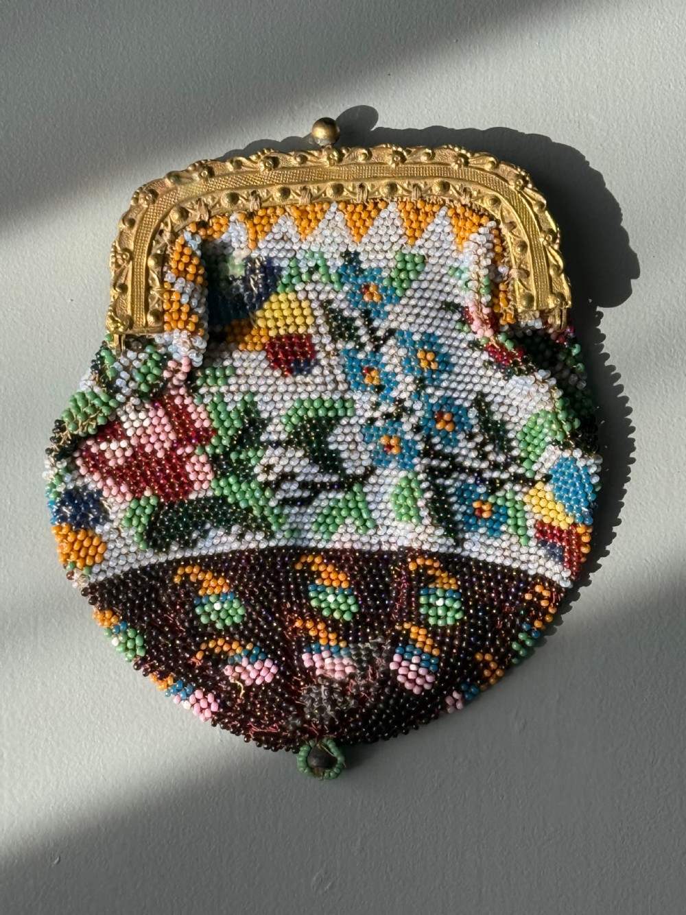 A collection of seven 1920s evening bags featuring micro-beaded floral patterns, silver mesh, and decorative metal frames arranged on a flat surface. View III