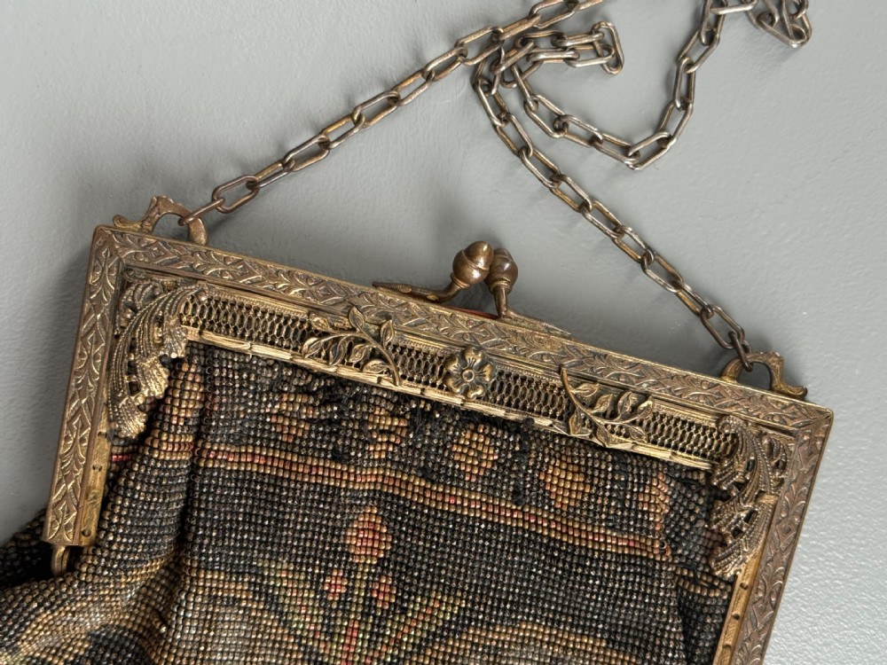 A collection of seven 1920s evening bags featuring micro-beaded floral patterns, silver mesh, and decorative metal frames arranged on a flat surface. View IV
