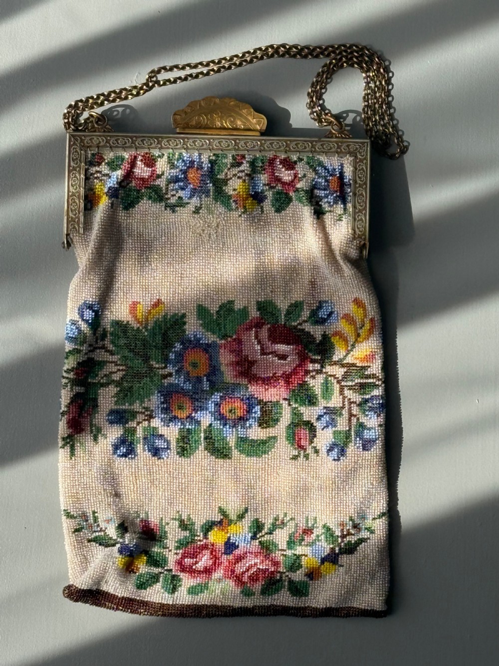 A collection of seven 1920s evening bags featuring micro-beaded floral patterns, silver mesh, and decorative metal frames arranged on a flat surface. View VII