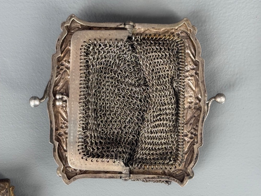 A collection of seven 1920s evening bags featuring micro-beaded floral patterns, silver mesh, and decorative metal frames arranged on a flat surface. View IX