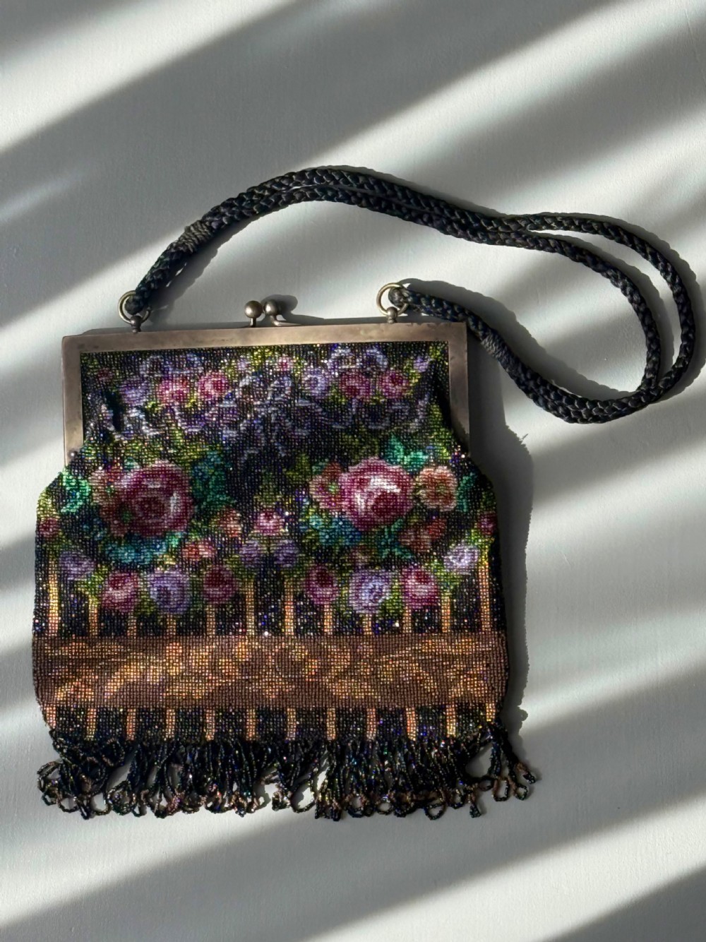 A collection of seven 1920s evening bags featuring micro-beaded floral patterns, silver mesh, and decorative metal frames arranged on a flat surface. View XI