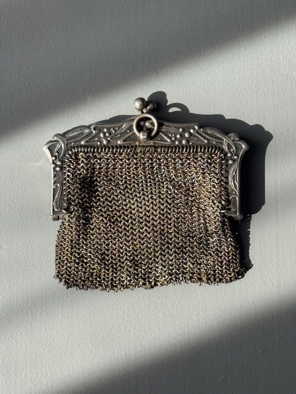 A collection of seven 1920s evening bags featuring micro-beaded floral patterns, silver mesh, and decorative metal frames arranged on a flat surface. View XII
