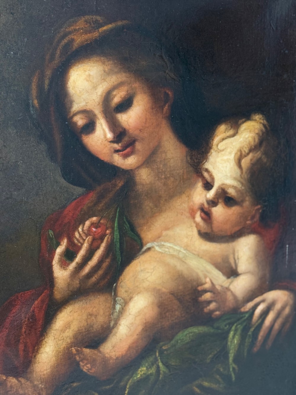 An early 18th-century Italian Baroque oil painting on canvas depicting the Madonna holding the infant Christ Child while holding cherries. View III