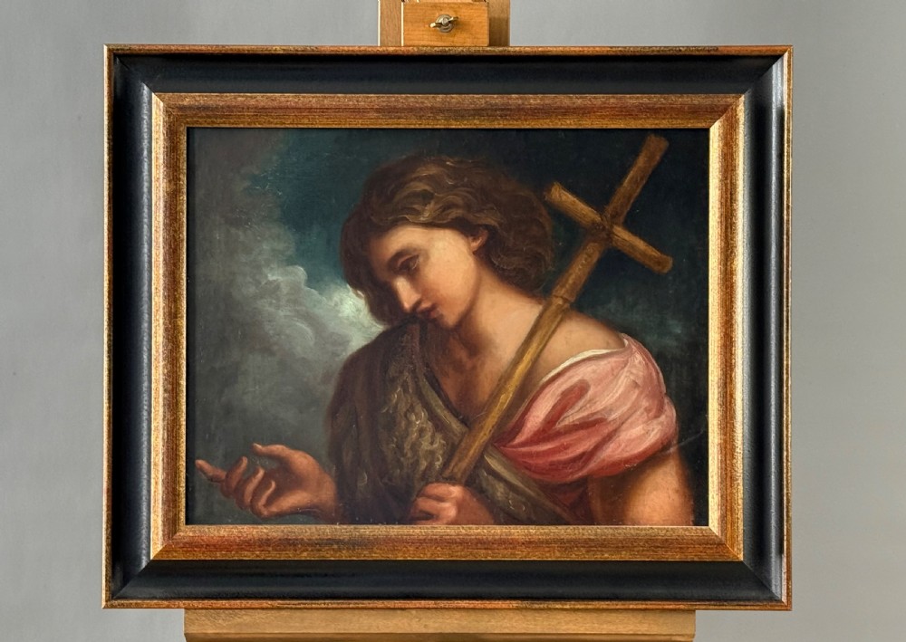 An 18th-century oil painting depicting Saint John the Baptist holding a reed cross, presented in an ebonised wooden frame with gilt moulding. View V