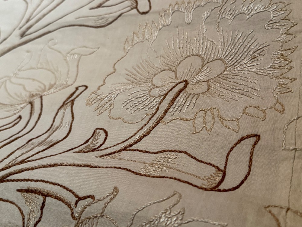 A cream-coloured Art Nouveau silk coverlet featuring hand-embroidered botanical motifs with a quilted border and pointed lace trim. View III