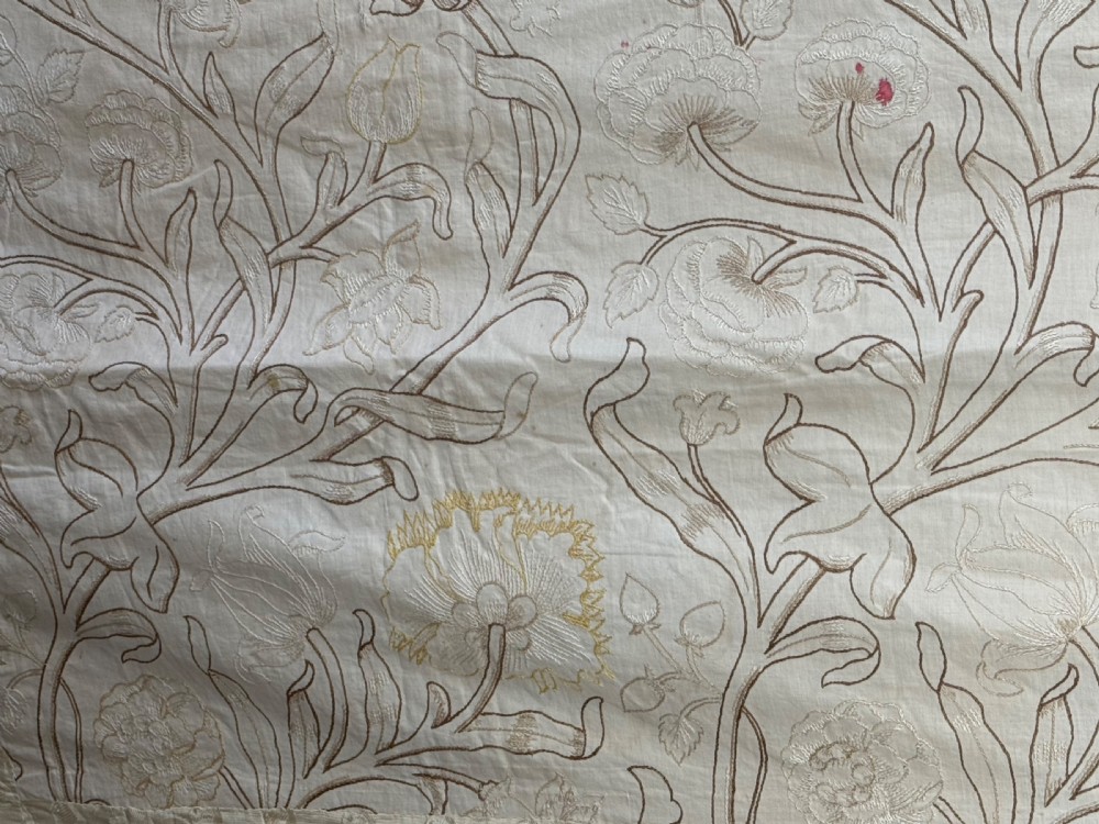 A cream-coloured Art Nouveau silk coverlet featuring hand-embroidered botanical motifs with a quilted border and pointed lace trim. View V