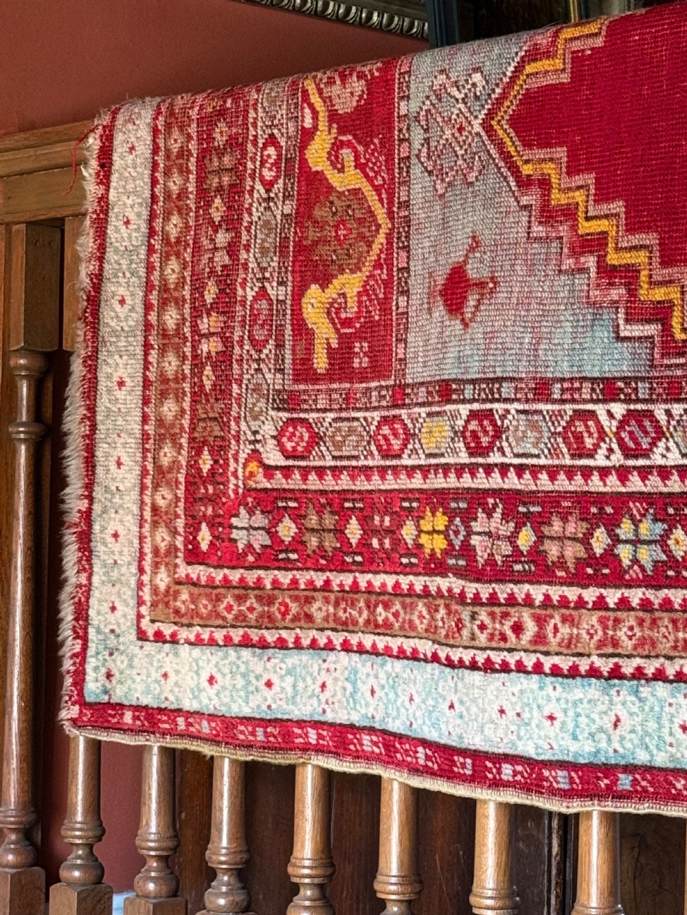 A late 19th-century Anatolian hand-knotted wool prayer rug featuring a central crimson mihrab niche motif surrounded by geometric borders in light blue, cream, and red. View II