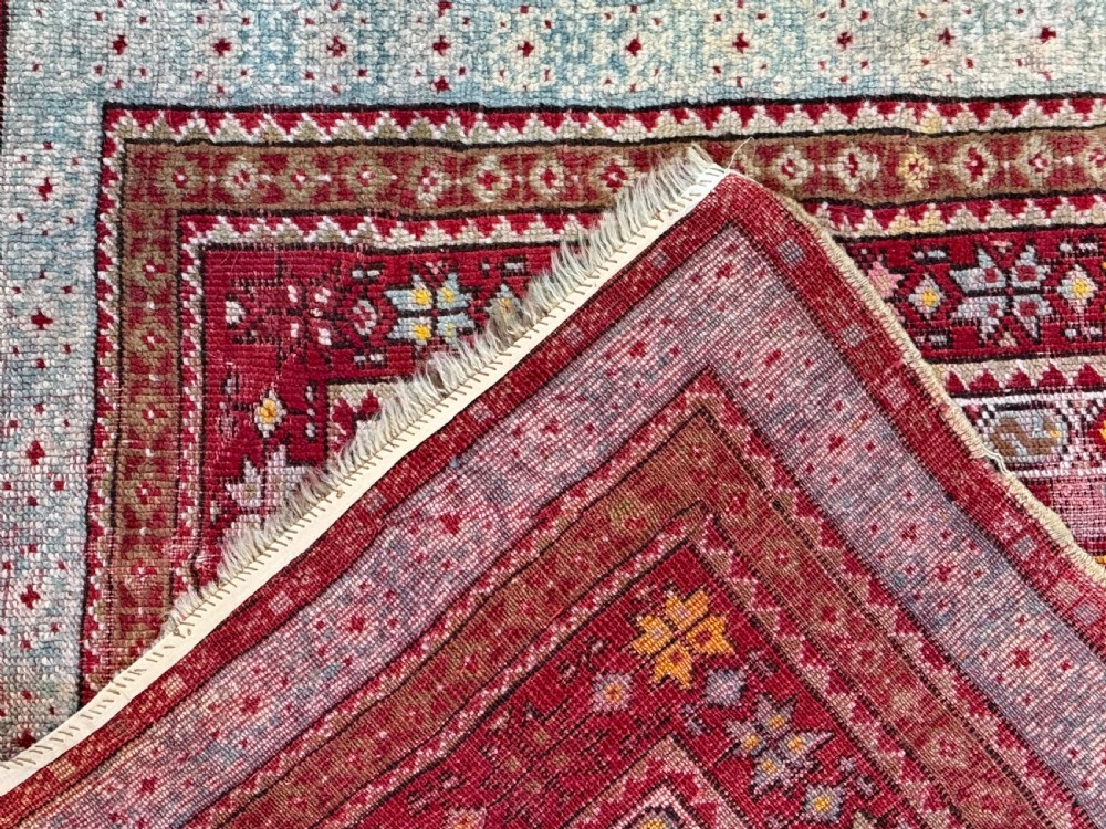 A late 19th-century Anatolian hand-knotted wool prayer rug featuring a central crimson mihrab niche motif surrounded by geometric borders in light blue, cream, and red. View IV