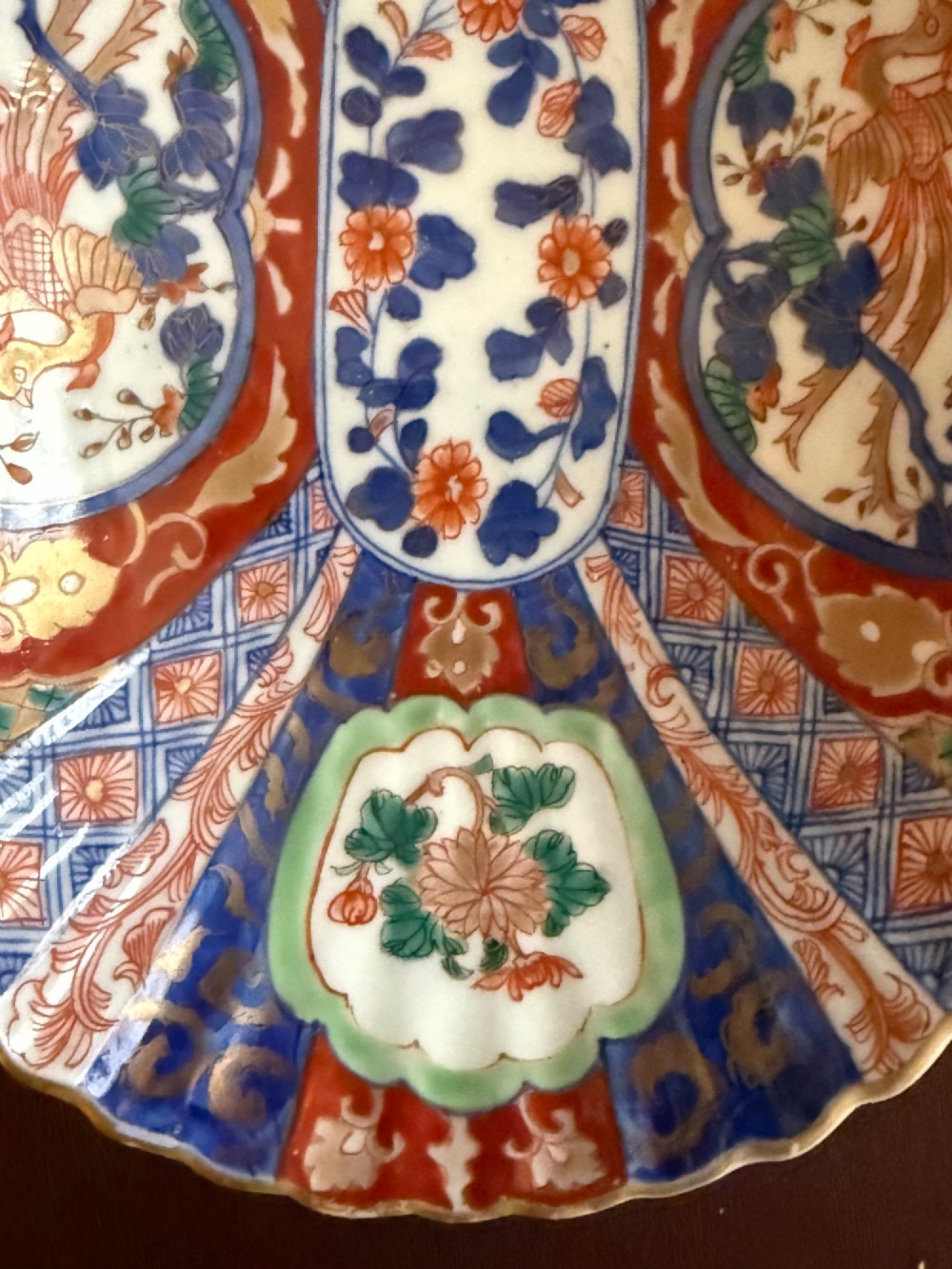 An oblong 19th-century Japanese Imari porcelain dish with scalloped edges, decorated with hand-painted cobalt blue, orange, green, and gold floral and bird patterns. View III