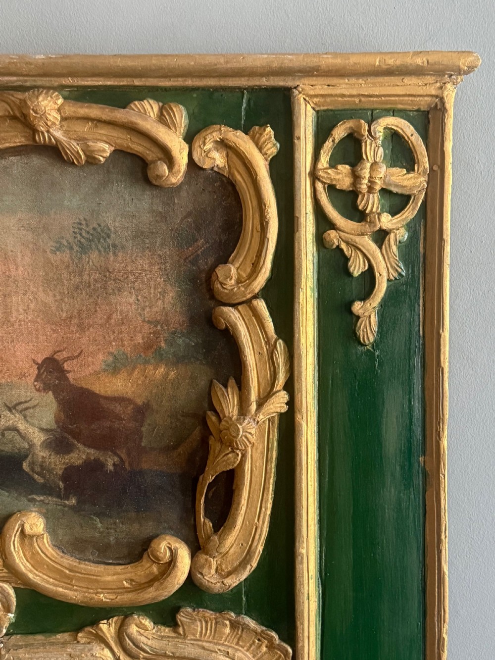 An eighteenth-century style French Rococo trumeau mirror featuring a painted green timber frame with carved gilded scrollwork surrounding an upper landscape painting and a lower rectangular mirror plate. View IV