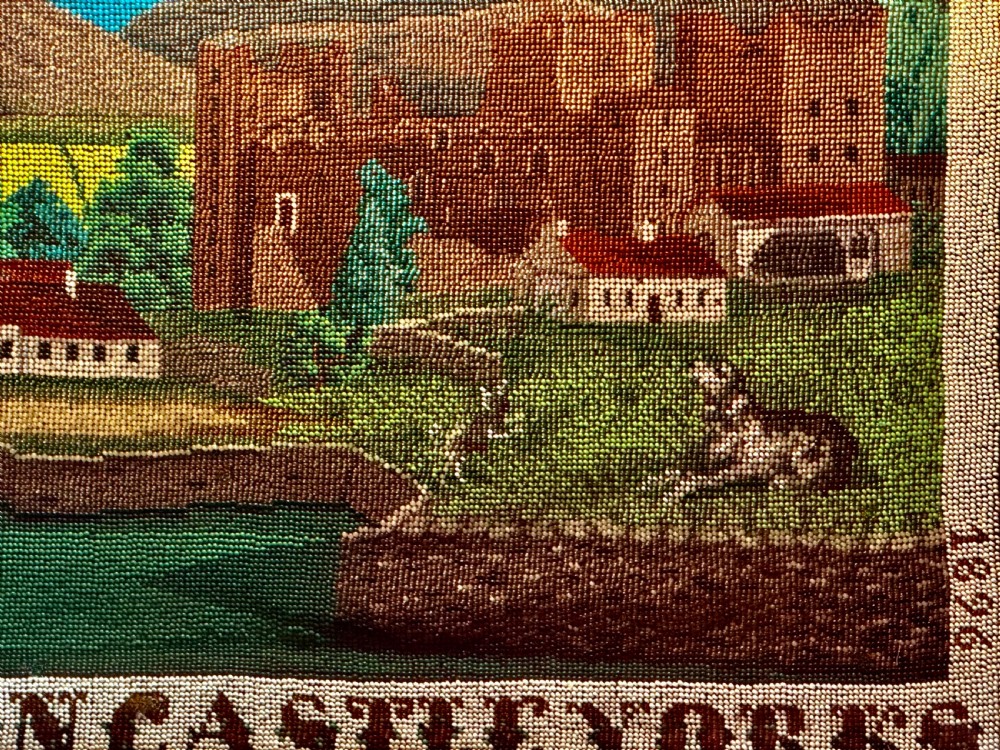 A framed 19th-century beadwork picture depicting Bolton Castle in Yorkshire with embroidered text and dates inside a gilded wooden frame. View VI