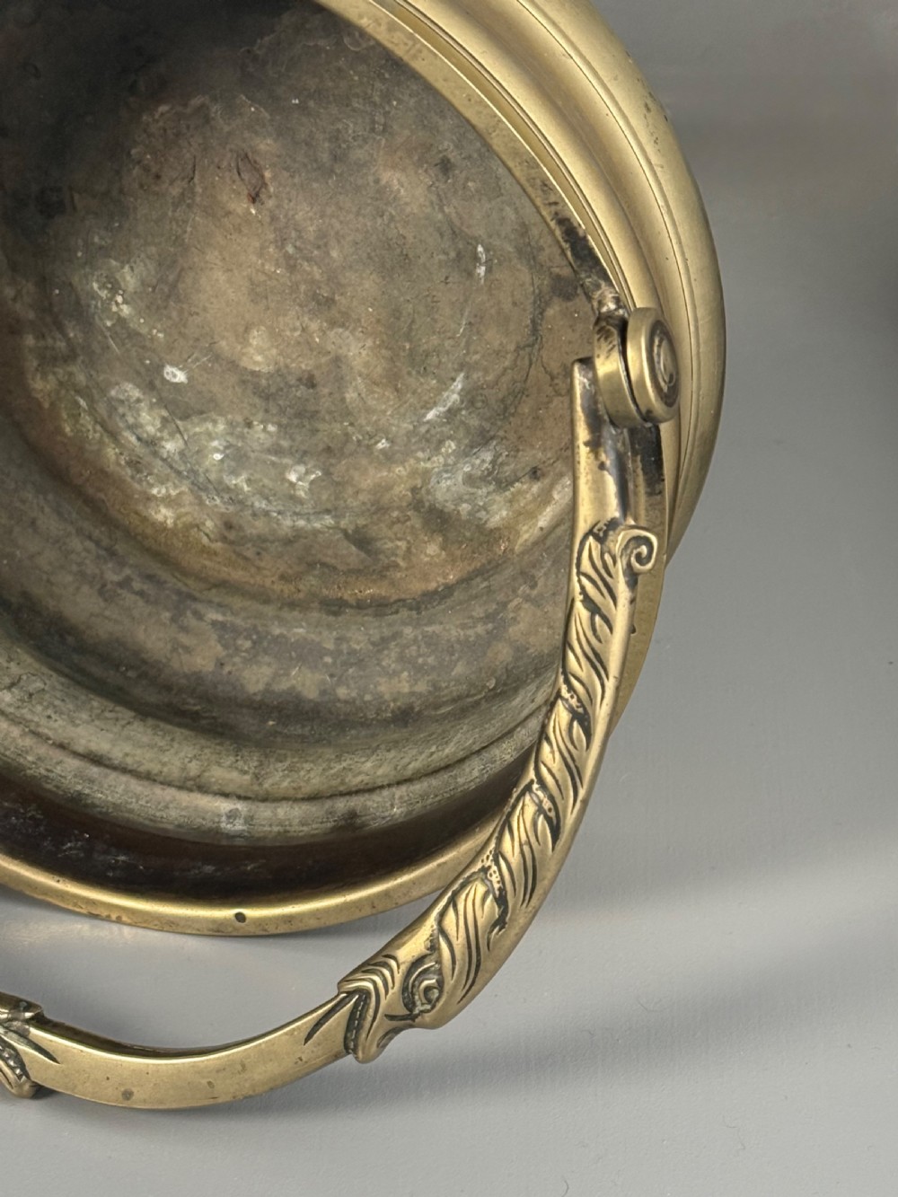 An aged brass urn with caryatid supports and a top finial lid, displayed alongside a brass vessel featuring a raised dragon-form handle. View V