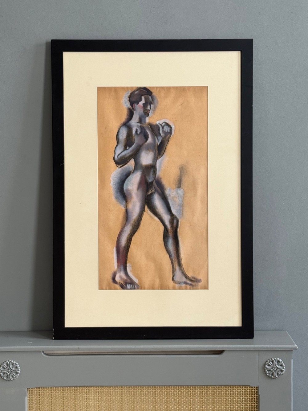 A framed charcoal and white gouache study of a standing male boxer in profile on beige paper within a cream mount and black wooden frame.