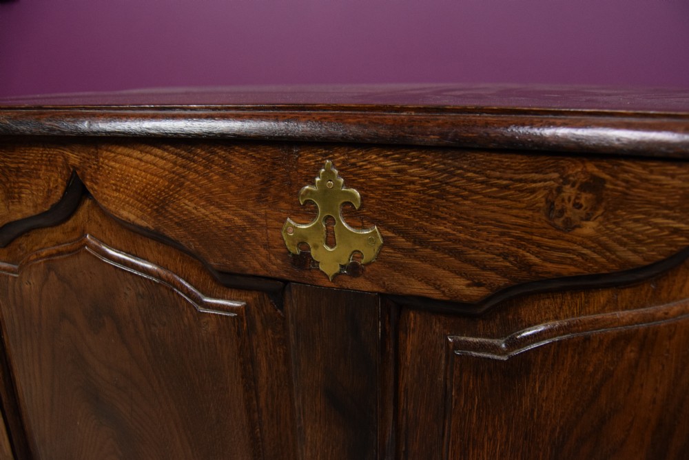 An early eighteenth-century dark oak Welsh coffer bach featuring two fielded arch panels, a brass escutcheon, and a shaped apron. View III