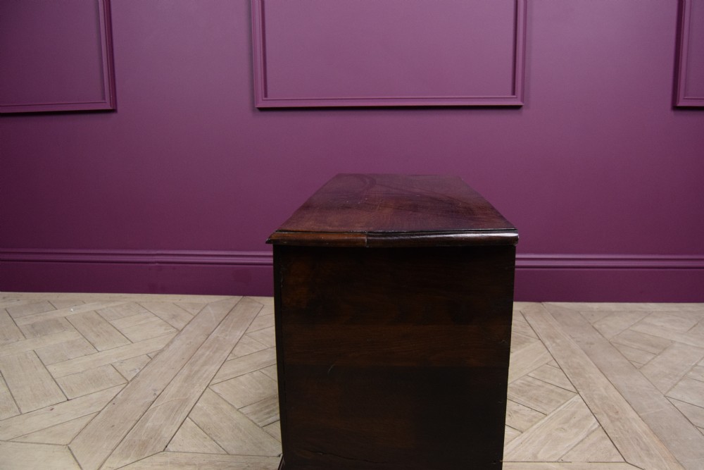 An early eighteenth-century dark oak Welsh coffer bach featuring two fielded arch panels, a brass escutcheon, and a shaped apron. View IV