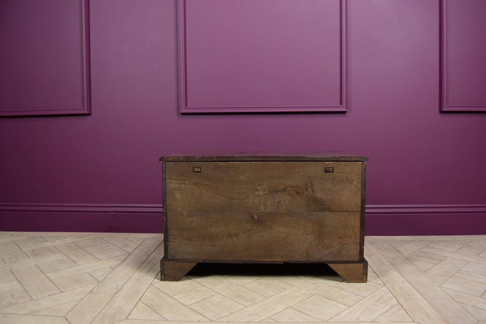 An early eighteenth-century dark oak Welsh coffer bach featuring two fielded arch panels, a brass escutcheon, and a shaped apron. View VI