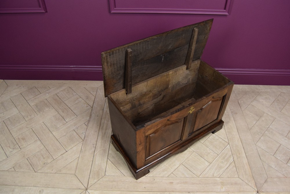 An early eighteenth-century dark oak Welsh coffer bach featuring two fielded arch panels, a brass escutcheon, and a shaped apron. View IX