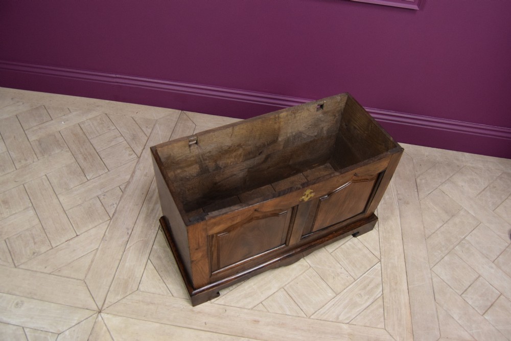An early eighteenth-century dark oak Welsh coffer bach featuring two fielded arch panels, a brass escutcheon, and a shaped apron. View XI
