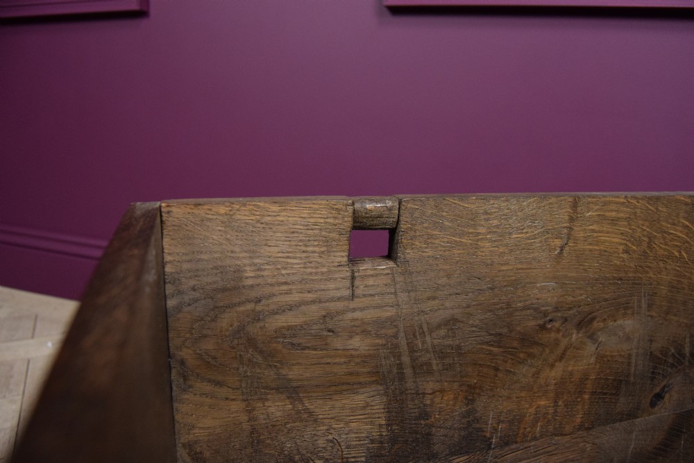 An early eighteenth-century dark oak Welsh coffer bach featuring two fielded arch panels, a brass escutcheon, and a shaped apron. View XII