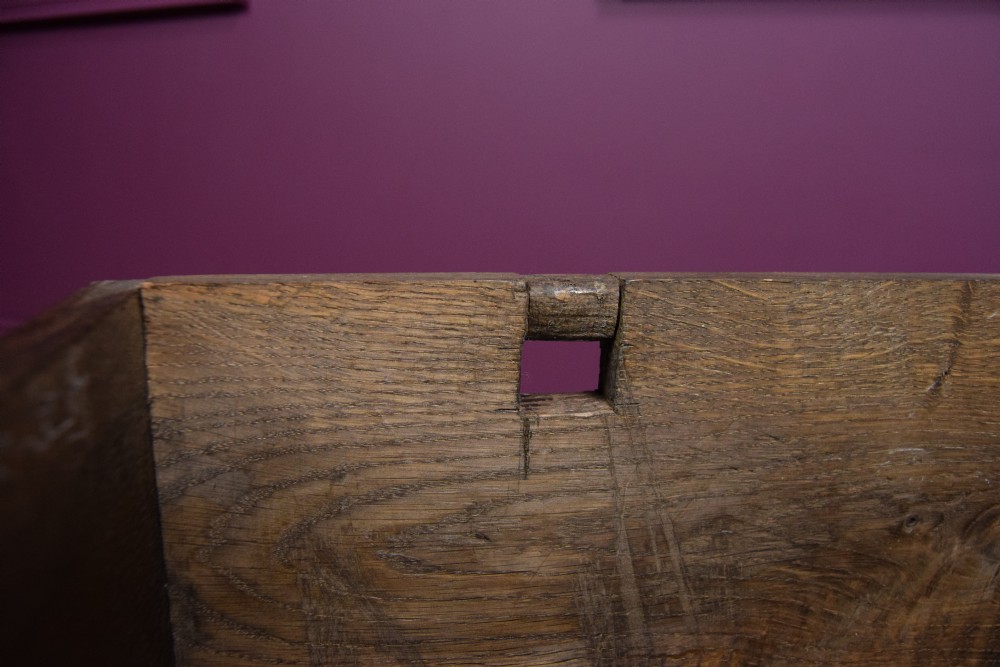 An early eighteenth-century dark oak Welsh coffer bach featuring two fielded arch panels, a brass escutcheon, and a shaped apron. View XIII