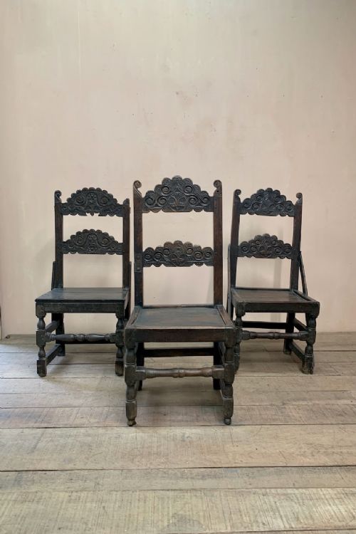 fig 1. A set of five 17th-century dark carved oak chairs displaying relief back panels and turned leg construction.