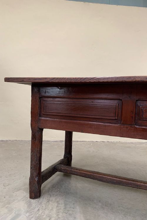 fig 1. A long dark brown antique French provincial console table with rectangular top, panelled drawers, straight legs, and a low H-stretcher.